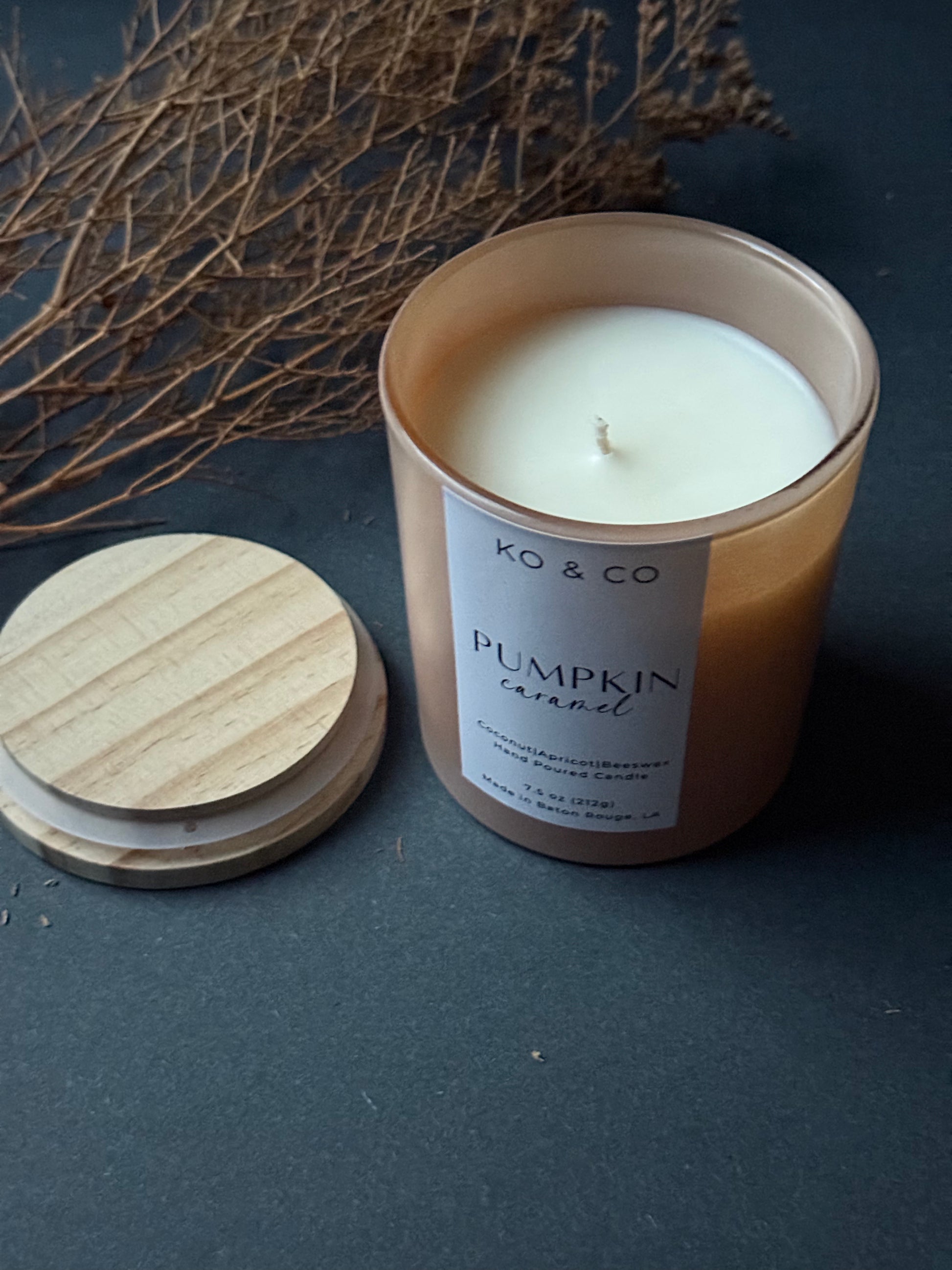KO&CO pumpkin caramel candle with wooden lid on a dark surface