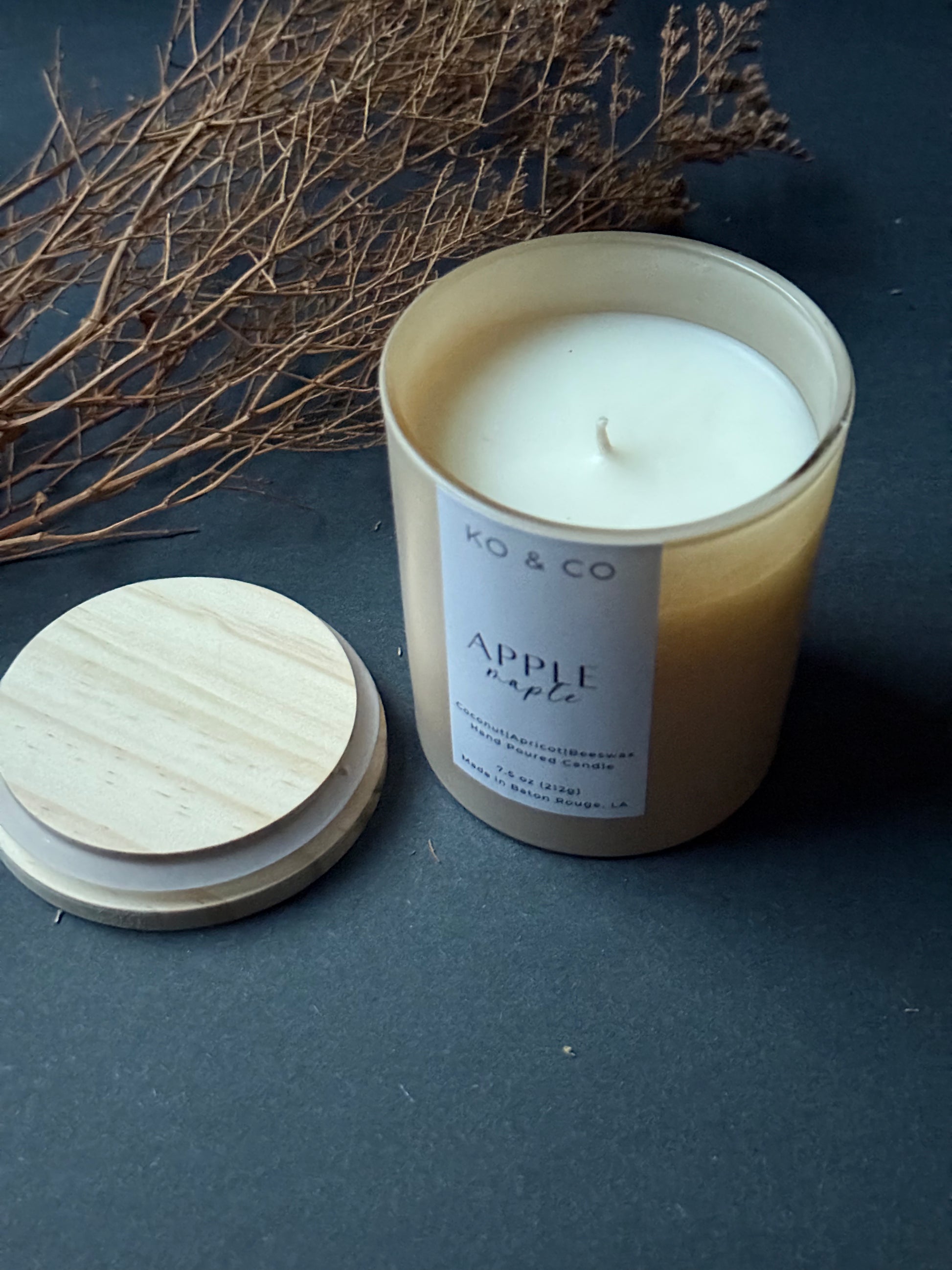 Candle with wooden lid and 'K&CO' label on a dark surface